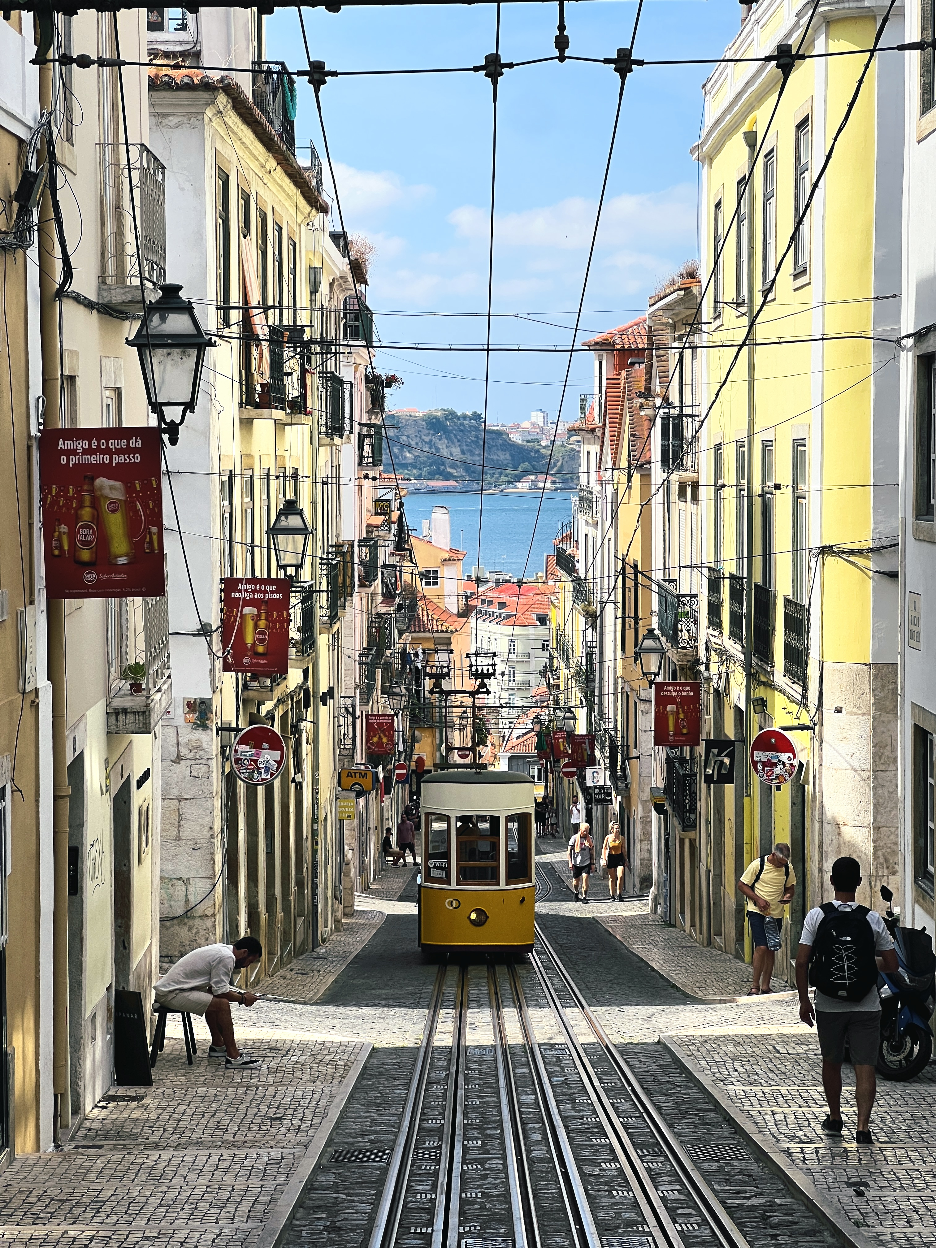 A yellow tram climbing a Lisbon street