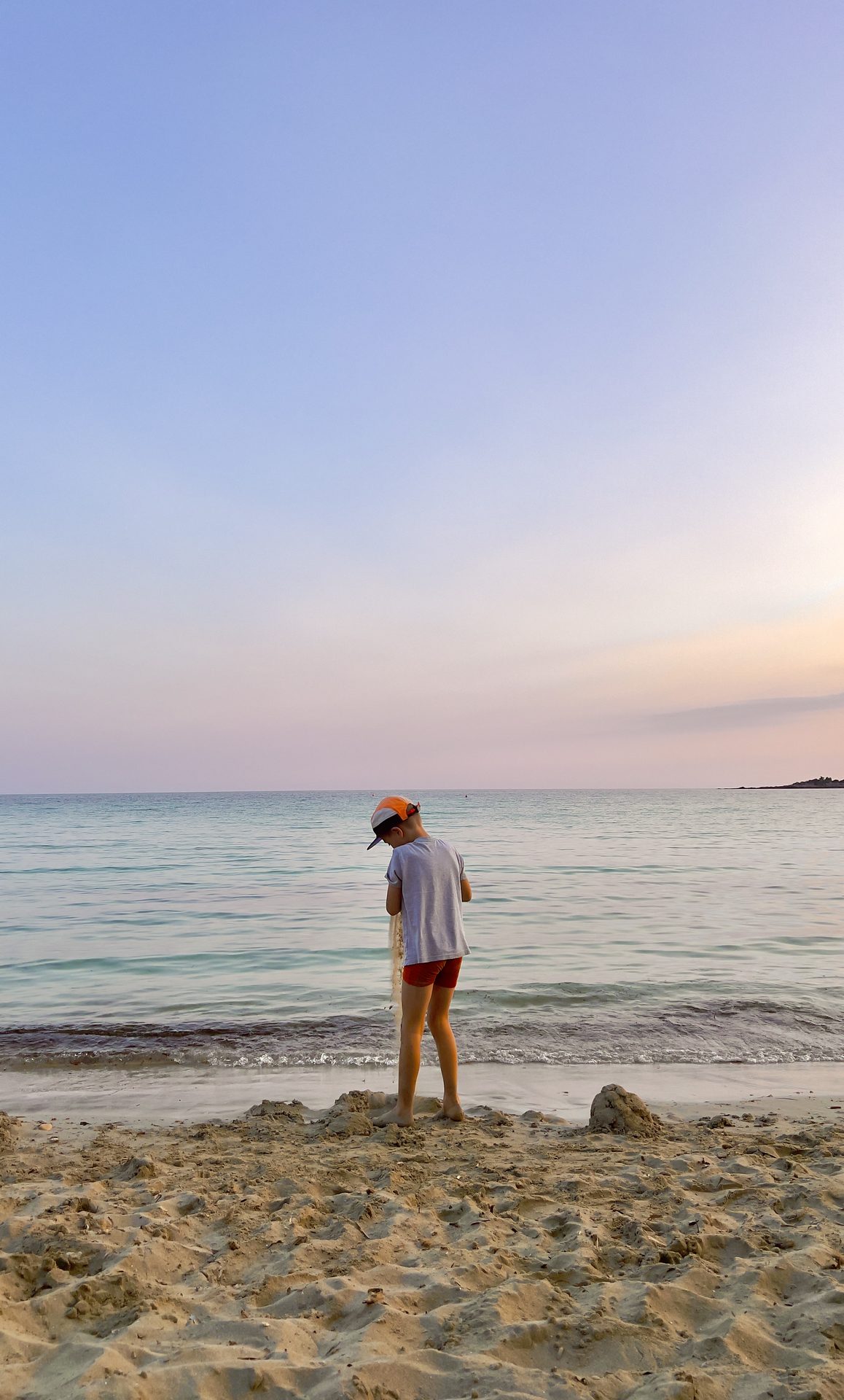 A boy at the shoreline at dusk